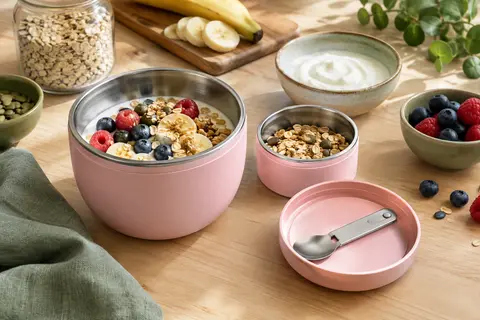 Bol muesli rose à deux compartiments avec cuillère en inox, présenté avec yaourt et céréales